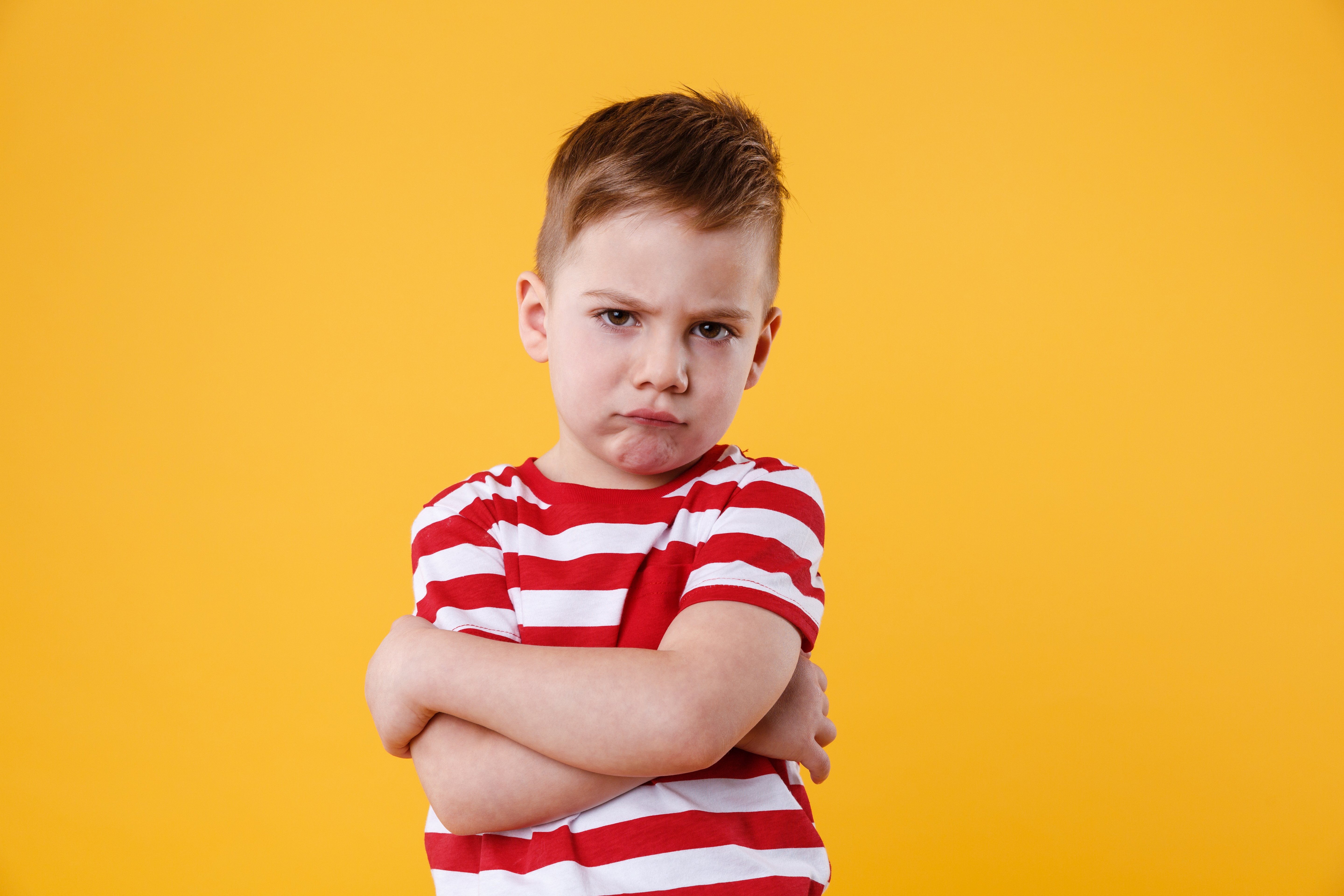 portrait-of-a-frowning-upset-little-boy-looking-at-camera-isolated-over-orange-backgro-SBI-303742960