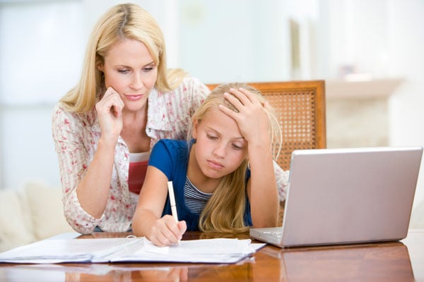 Girl working on homework at home with mom
