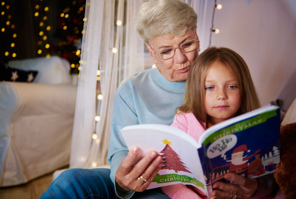 grandmother-and-granddaughter-reading-storybook-in-bed